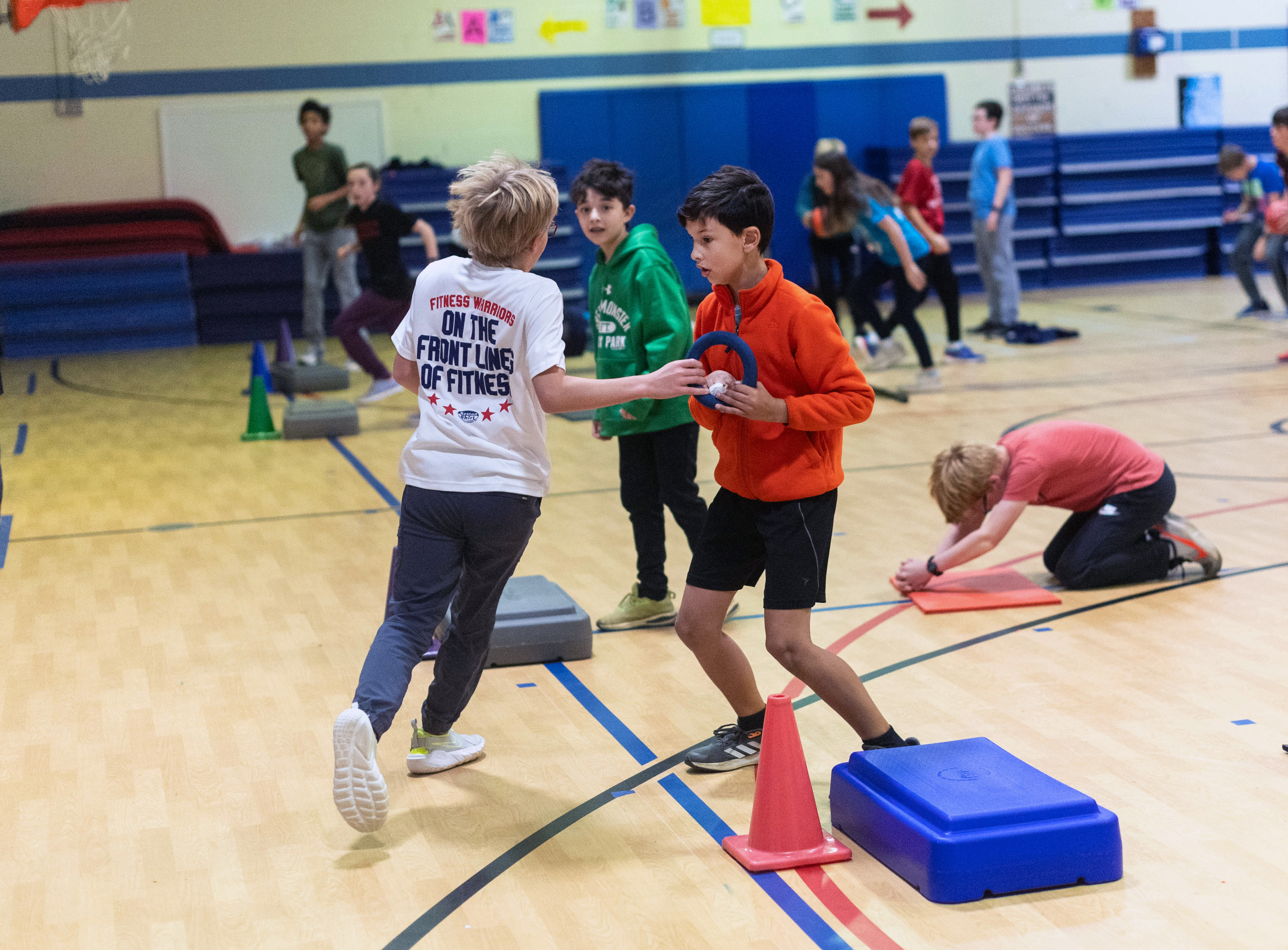 One sixth-grader passes a ring to another during a workout competition in a Fitness Warriors class.